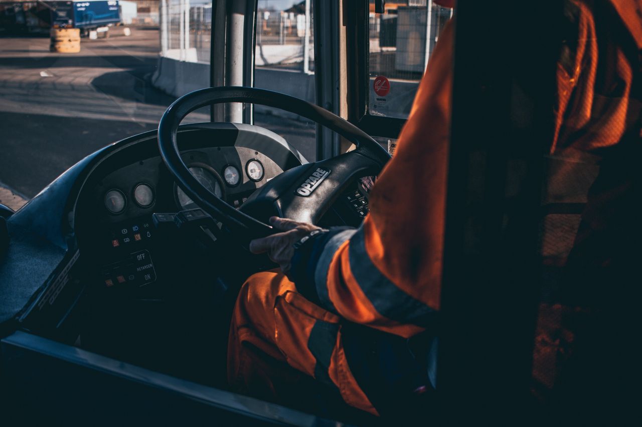 services-02 Bus driver operating vehicle from the cockpit in an industrial setting, showcasing control and focus.